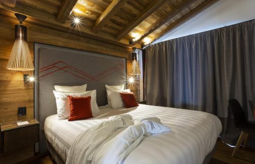 a bedroom with a bed with white sheets and red pillows at Hôtel Alparena & Spa - 4 étoiles in La Rosière
