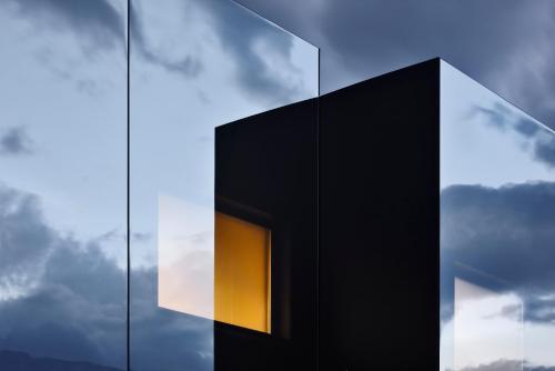 a window in the side of a black building at Mirror Houses in Bolzano