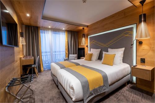 a hotel room with a large bed with yellow pillows at Hôtel Alparena & Spa - 4 étoiles in La Rosière