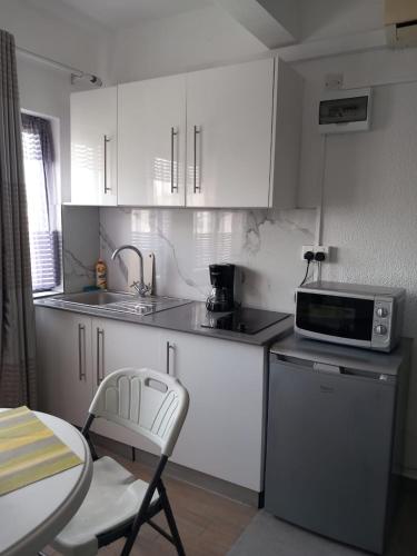 a kitchen with white cabinets and a table and a microwave at Ibis Tourist Residence 1 in Mahébourg