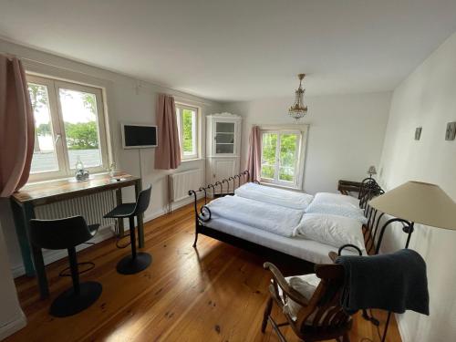 a bedroom with a bed and a desk and windows at Burger Fährhaus in Burgerfeld