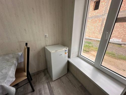 a small refrigerator in a room with a window at Pamko in Naryn