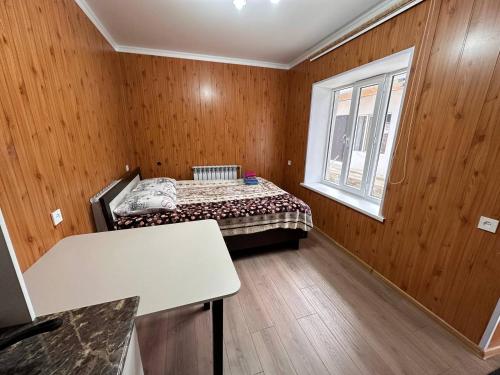 a small room with a bed and a window at Pamko in Naryn