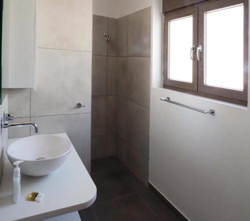 une salle de bain blanche avec un lavabo et une fenêtre dans l'établissement Plakopoules Beach Apartments, à Siteía
