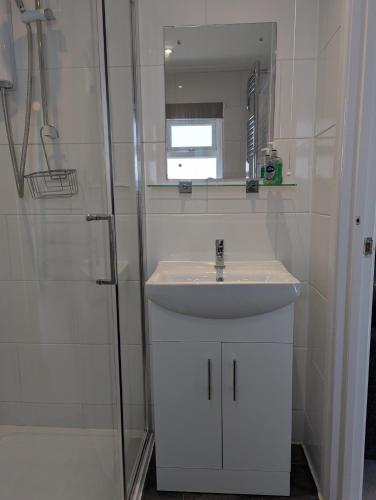 a white bathroom with a sink and a mirror at Turnstone Bungalow in Hunstanton