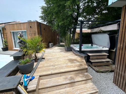 a backyard with a wooden deck and a hot tub at Little Paradise in Belin-Beliet