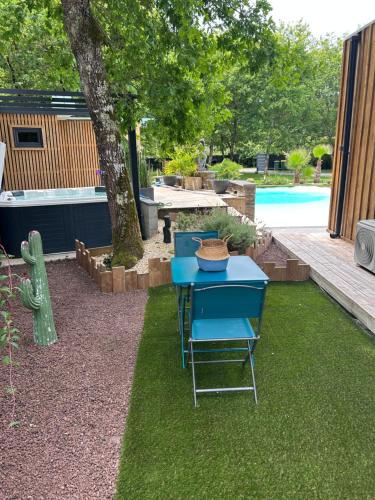 a blue table and chairs in a yard with a pool at Little Paradise in Belin-Beliet