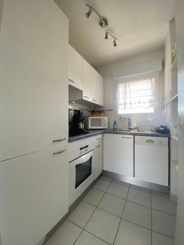 une cuisine blanche avec des armoires blanches et un micro-ondes dans l'établissement The shores of the sea, à Aresquies