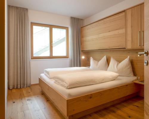 a bedroom with a bed with a wooden headboard and a window at Ferienhof Neusacher Moser in Weissensee