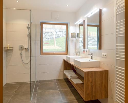 a bathroom with a sink and a glass shower at Ferienhof Neusacher Moser in Weissensee