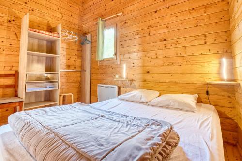 a bedroom with a bed in a wooden cabin at Chalet Rapiette in Salignac Eyvigues