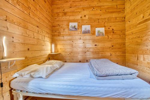 a bedroom with a bed in a wooden room at Chalet Rapiette in Salignac Eyvigues