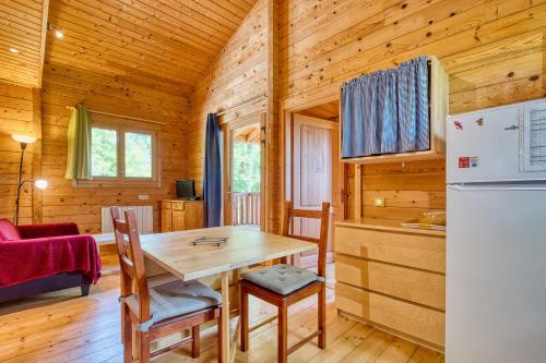 a kitchen and dining room with a table and a refrigerator at Chalet Rapiette in Salignac Eyvigues