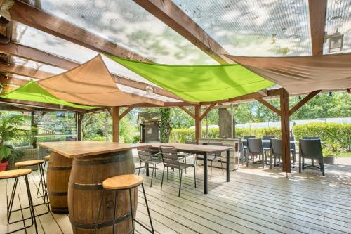a patio with tables and chairs and a green canopy at Chalet Rapiette in Salignac Eyvigues