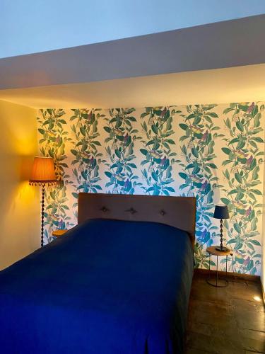 a bedroom with a blue bed and a floral wallpaper at La maison d'en haut in Josselin