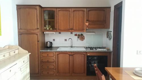 a kitchen with wooden cabinets and a sink at Casa Maggy in Budoni