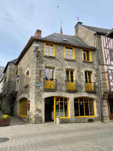 un grand bâtiment en pierre avec des portes et des fenêtres jaunes dans l'établissement La maison d'en haut, à Josselin