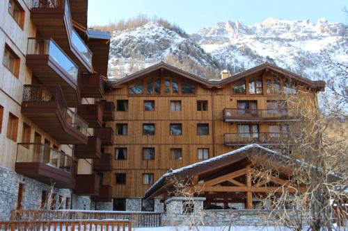 a large building with snow covered mountains in the background at Les Clarines in Le Joseray