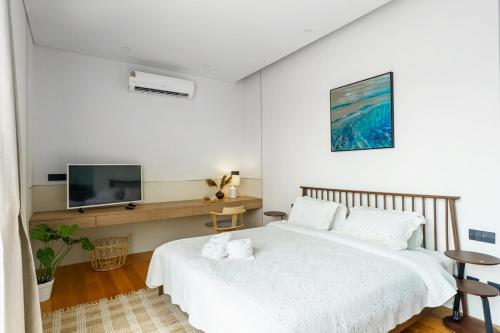 a white bedroom with two beds and a tv at Modern 3 Bdr Villa Tree O'Clock Bangtao With a Pool in Ban Pak Lak