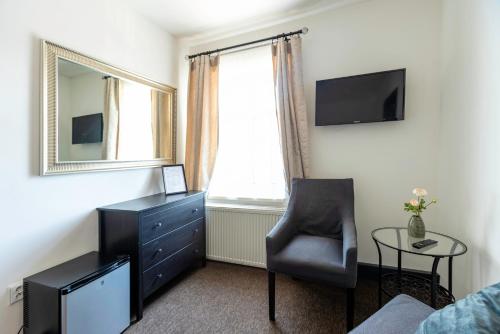 a bedroom with a chair and a dresser and a mirror at Restaurace Hotel Praha in Nižbor