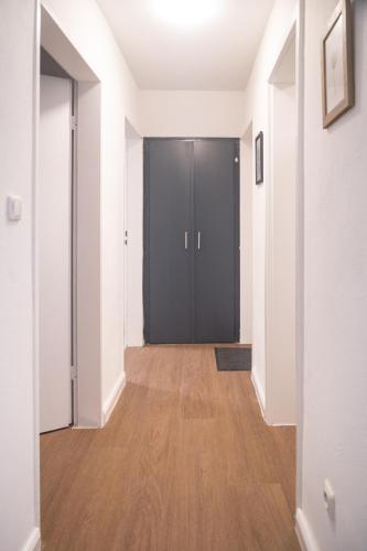 a hallway with a black door and a wooden floor at Apartment in Lüneburg, 2 Zimmer, Küche, 80 qm in Lüneburg