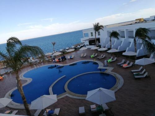 a swimming pool with chairs and umbrellas next to the ocean at Miral Resort in Ain Sokhna