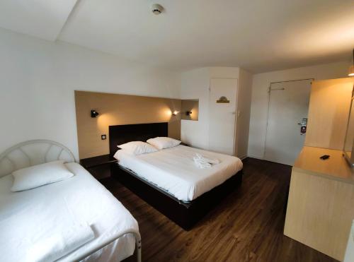 a hotel room with two beds and a refrigerator at Hôtel Akena Pierrelaye in Pierrelaye