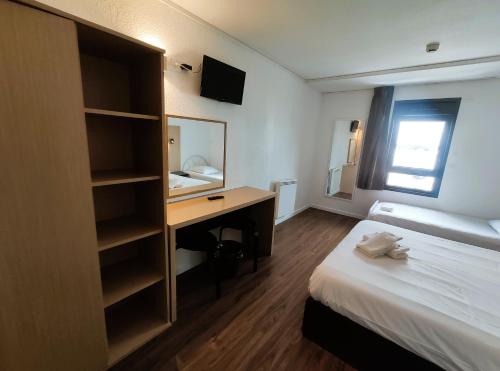 a hotel room with a desk and a bed at Hôtel Akena Pierrelaye in Pierrelaye