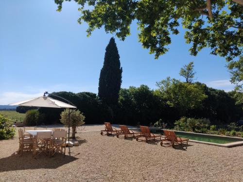 un groupe de chaises, de tables et d'un parasol dans l'établissement Cœur de Mas entre Alpilles et Camargue avec piscine et climatisation - 2 chambres, à Arles