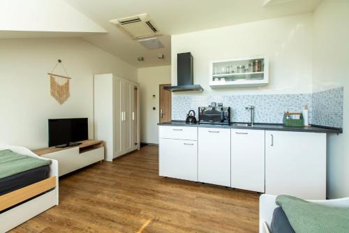 a kitchen with white cabinets and a television in a room at Restaurace Hotel Praha in Nižbor