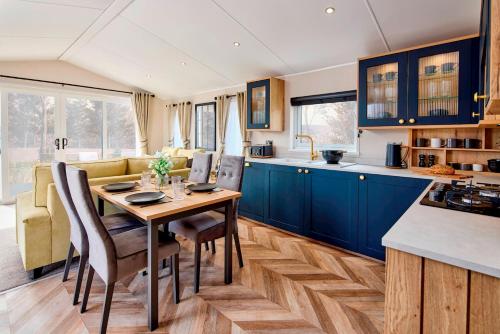 a kitchen with blue cabinets and a wooden table and chairs at Addlethorpe Golf & Country Club, Ingoldmells in Addlethorpe
