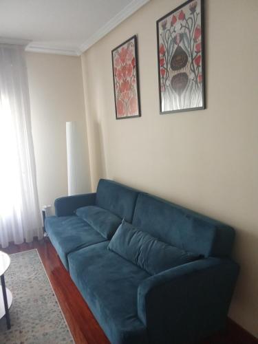a blue couch in a living room with two pictures on the wall at FUENTETRIGO III Medina de Pomar in Medina de Pomar