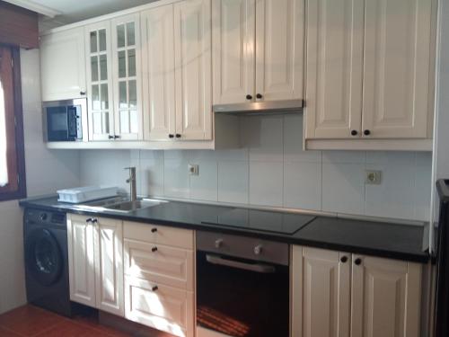 a kitchen with white cabinets and a black counter top at FUENTETRIGO III Medina de Pomar in Medina de Pomar