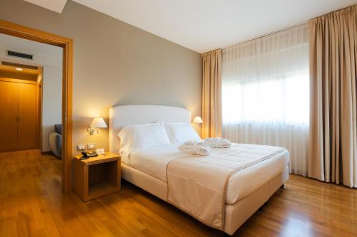 a bedroom with a large white bed and a window at Hotel Touring in Carpi