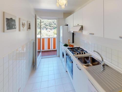 une cuisine blanche avec une cuisinière et une fenêtre dans l'établissement 2P dernier étage, parking privé, climatisation, WiFi - FR-1-196-159, à Menton