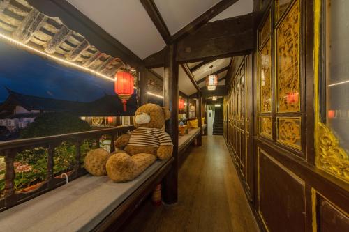 a teddy bear sitting on a bench in a restaurant at Yiyuan Snow Mountain View Historical Naxi House - Lijiang Old Town Mufu branch in Lijiang