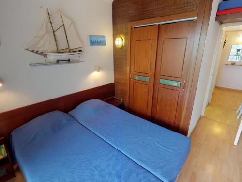 - une petite chambre avec un lit bleu et un bateau sur le mur dans l'établissement 2P à Menton avec Piscine, Terrasse, Parking et Proche Plages - FR-1-196-194, à Menton