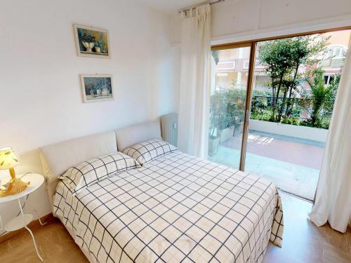 une chambre avec un lit et une grande fenêtre dans l'établissement Charmant 2P avec terrasse, garage privé, proche centre et plages de Menton - FR-1-196-210, à Menton