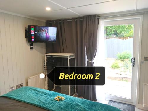 德比Peaceful garden guesthouse, Sleep 4, Parking, Private entrance, SuperFast Wifi的一间卧室设有一张带电视和窗户的床。