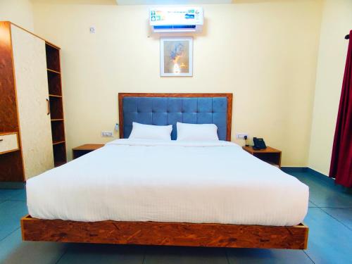 a bedroom with a large bed with a blue headboard at Pakalakam Resort in Cheruppulasseri