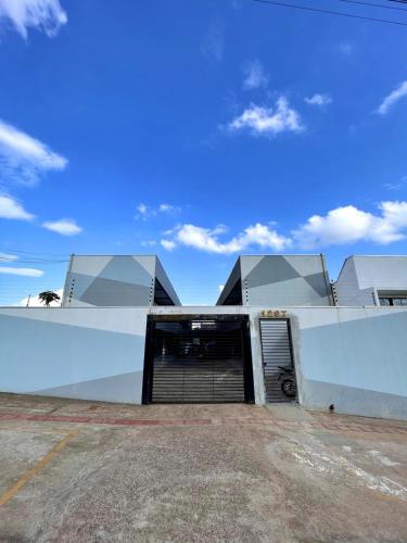 a white building with a garage with a sky at Kitnet Luz do Mar - 04 com ar condicionado in Maringá
