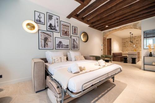 une grande chambre avec un grand lit et des tableaux au mur dans l'établissement Luxury 2BR - Place des Vosges - Le Marais, à Paris