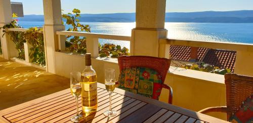 a table with two glasses and a bottle of wine on a balcony at Apartments Mihael in Celina