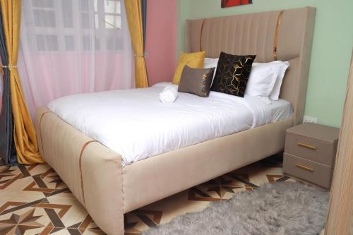 ナイロビにあるMWANGO HOMES - Elegant, Cozy, Homely 1-bedroom at Mirema Driveの白いシーツと枕が付いた大きなベッドのある寝室