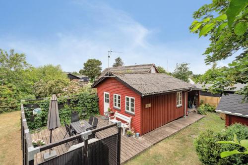 a red tiny house with a deck and an umbrella at Lifestyle Near Sea And Town in Nykøbing Mors
