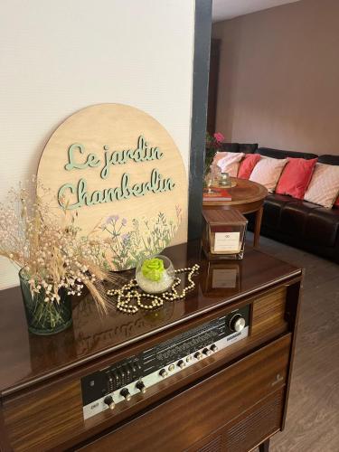 a living room with a table with a sign on it at Le jardin Chamberlin, Maison d'hôtes in Savigny-sur-Orge