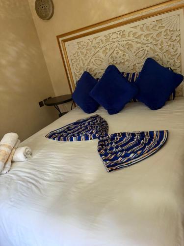 a white bed with blue pillows and a headboard at Riad Golf Stinia 1 in Meknès