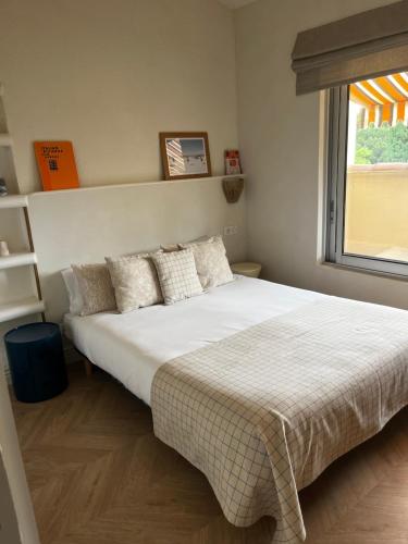 une chambre avec un grand lit blanc avec une fenêtre dans l'établissement Pramousquier -Vue mer - 3 pièces - rénové à neuf, au Lavandou