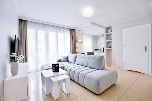 biały salon z kanapą i stołem w obiekcie Promenada by Baltic Home w Świnoujściu