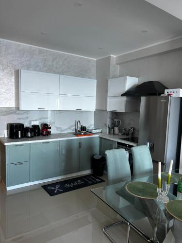 une cuisine avec des armoires blanches et une table en verre dans l'établissement Sea Front View - FRONT DE MER ET VUE PANORAMIQUE, à Nice